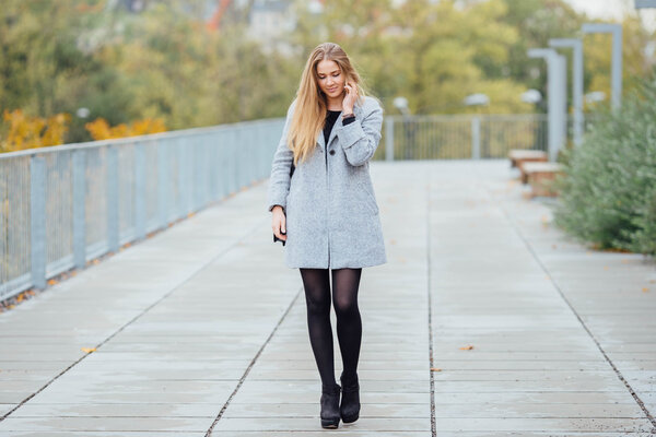 Blonde hair woman walking on the street and talking on telephone