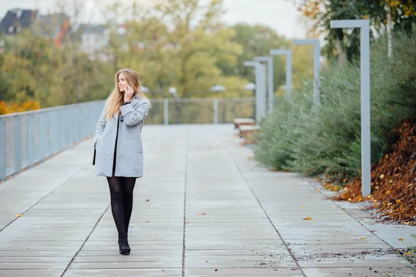 Femme aux cheveux blonds marchant dans la rue et parlant au téléphone — Photo