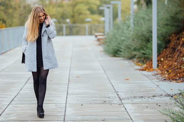 Blonde hair woman walking on the street and talking on telephone — Stock Photo, Image