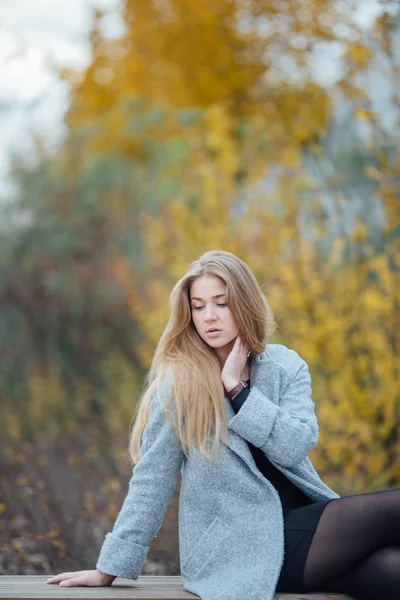 Blond włosy kobieta siedzi na ławce i uśmiech — Zdjęcie stockowe