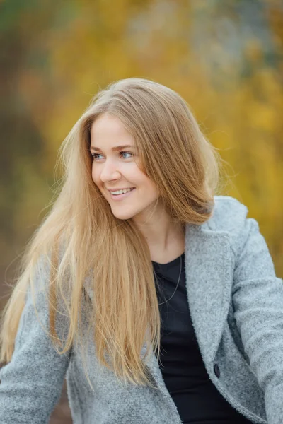 Ξανθά μαλλιά γυναίκα που κάθεται στο πάγκο και χαμόγελο — Φωτογραφία Αρχείου