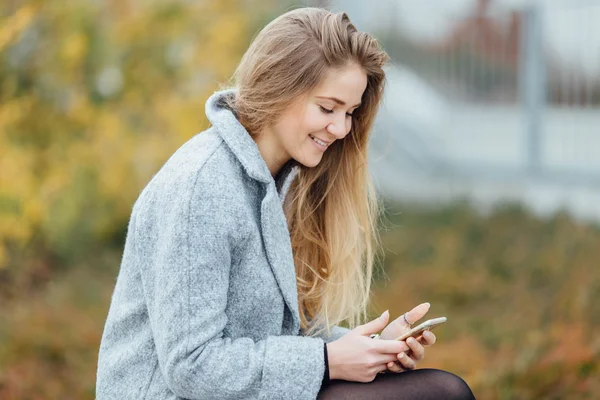 Блондинка, сидящая на скамейке и улыбающаяся — стоковое фото