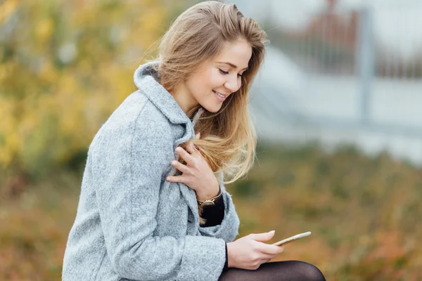 Femme aux cheveux blonds assise sur le banc et sourire — Photo