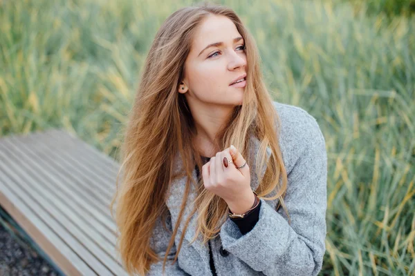 Rubia mujer de pelo sentado en el banco y sonrisa —  Fotos de Stock