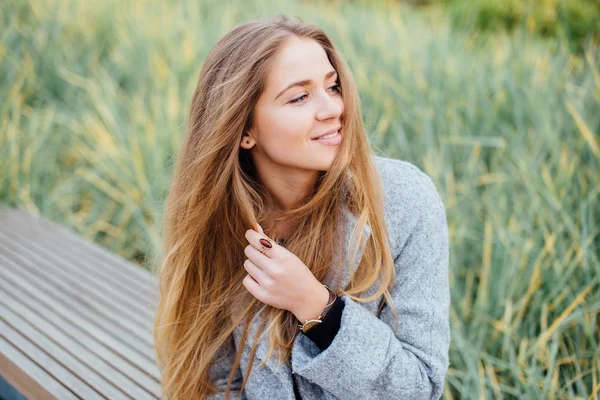 Rubia mujer de pelo sentado en el banco y sonrisa —  Fotos de Stock