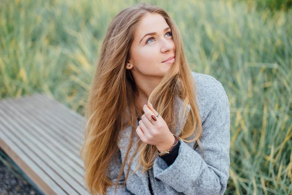 Rubia mujer de pelo sentado en el banco y sonrisa — Foto de Stock