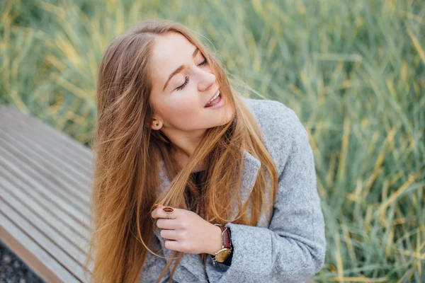 Blonde haren vrouw zittend op de Bank en glimlach — Stockfoto