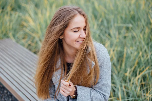 Femme aux cheveux blonds assise sur le banc et sourire — Photo