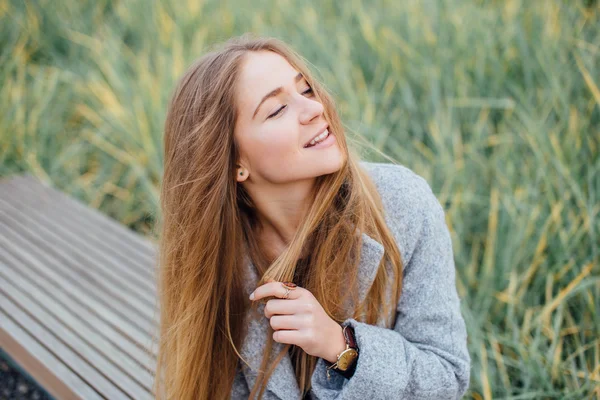 Rubia mujer de pelo sentado en el banco y sonrisa — Foto de Stock