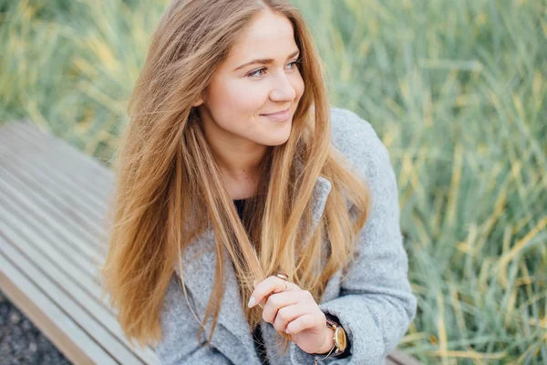 Bionda capelli donna seduta sulla panchina e sorridere — Foto Stock