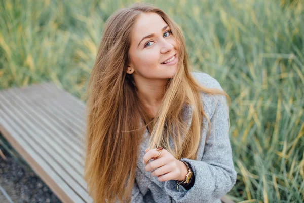 Rubia mujer de pelo sentado en el banco y sonrisa — Foto de Stock