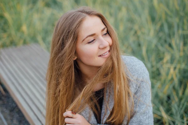 Rubia mujer de pelo sentado en el banco y sonrisa —  Fotos de Stock