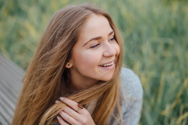 Rubia mujer de pelo sentado en el banco y sonrisa — Foto de Stock