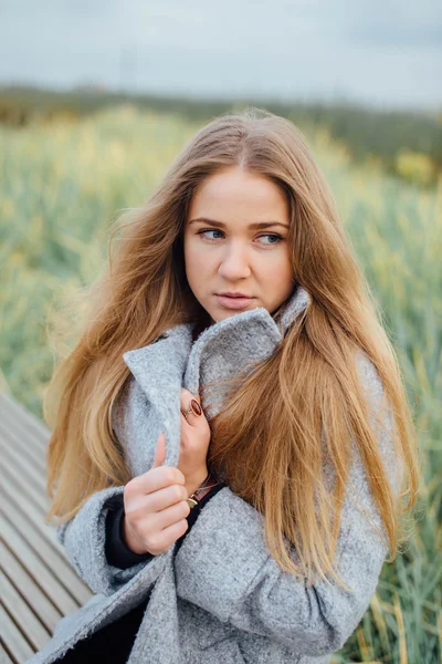 Blonda hår kvinna sitter på bänken och leende — Stockfoto