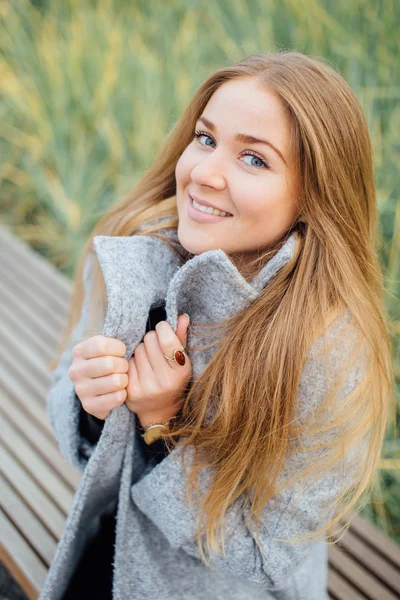 Rubia mujer de pelo sentado en el banco y sonrisa — Foto de Stock