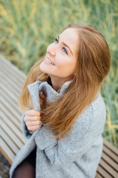 Rubia mujer de pelo sentado en el banco y sonrisa — Foto de Stock