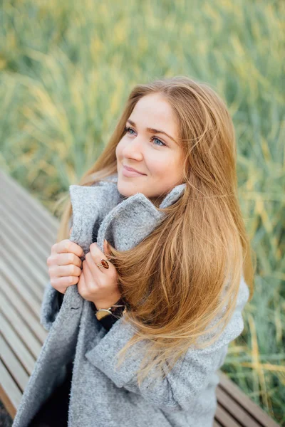 Rubia mujer de pelo sentado en el banco y sonrisa — Foto de Stock