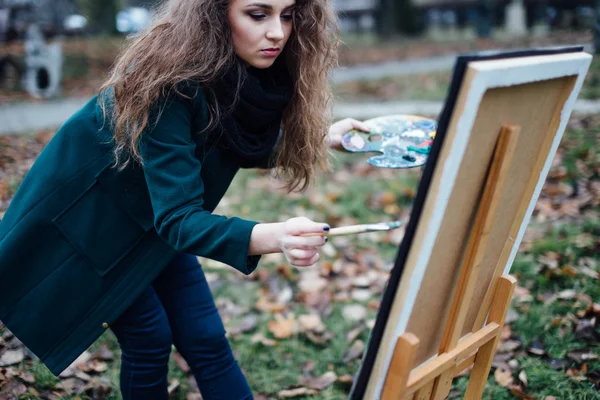 Nuori nainen piirustus maalausteline puistossa taustalla — kuvapankkivalokuva