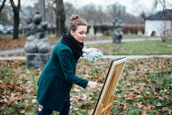 Genç kadın şövale içinde park arka plan üzerinde çizim — Stok fotoğraf