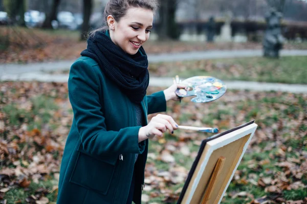 Jeune femme dessinant dans le chevalet sur le fond du parc — Photo