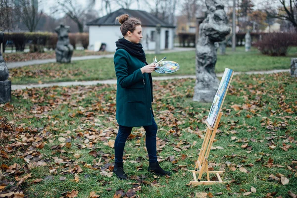 Jeune femme dessinant dans le chevalet sur le fond du parc — Photo