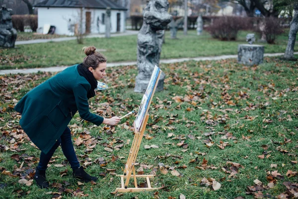 Genç kadın şövale içinde park arka plan üzerinde çizim — Stok fotoğraf