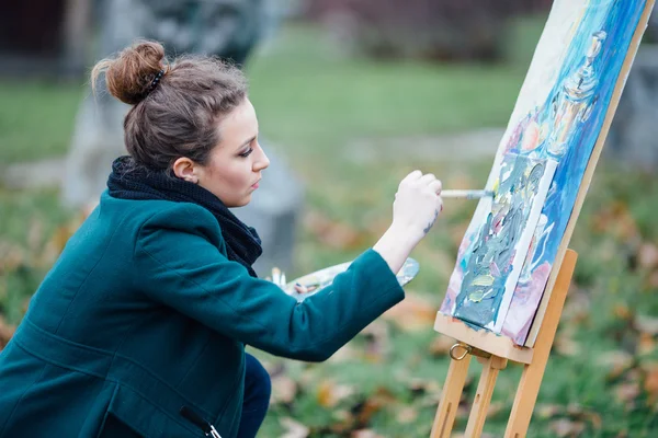 Jeune femme dessinant dans le chevalet sur le fond du parc — Photo