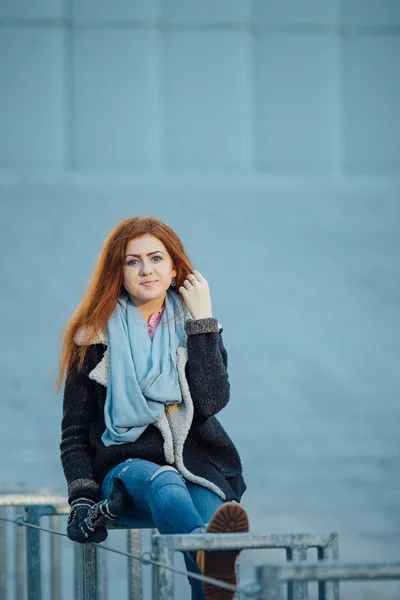 Young girl sitting on the metal bench near modern architecture — Stockfoto