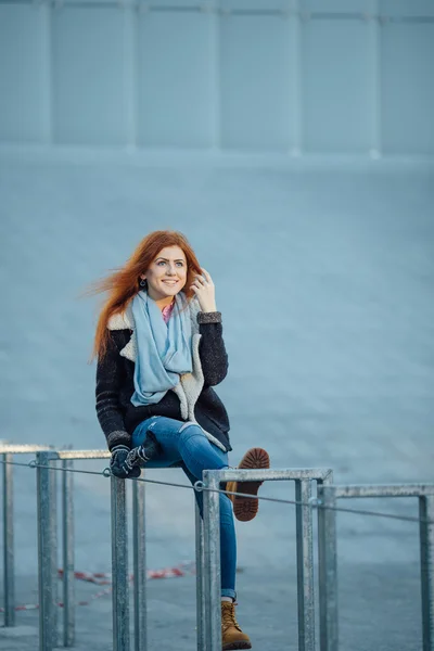 Chica joven sentada en el banco de metal cerca de la arquitectura moderna — Foto de Stock