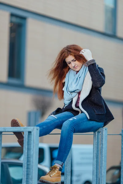 Young girl sitting on the metal bench near modern architecture — Stock Fotó