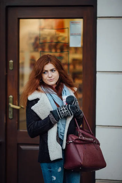 Fille aux cheveux roux debout près du café et tenant une tasse — Photo