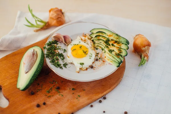 Desayuno compuesto por tostadas, huevos, aguacate, cebolla, papel y ajo — Foto de Stock