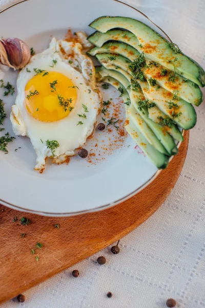 Desayuno compuesto por tostadas, huevos, aguacate, cebolla, papel y ajo — Foto de Stock