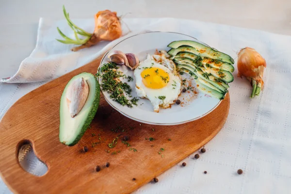 Desayuno compuesto por tostadas, huevos, aguacate, cebolla, papel y ajo — Foto de Stock