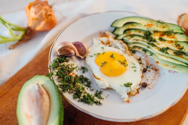 Desayuno compuesto por tostadas, huevos, aguacate, cebolla, papel y ajo — Foto de Stock