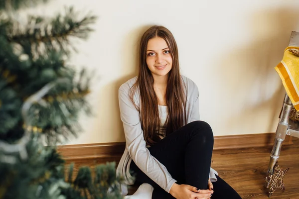 Ragazza solitaria seduta dietro l'albero di Natale con regali — Foto Stock