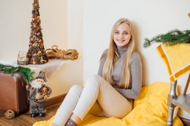 Duvara yakın oturan ve hediyelerini açmayı sarışın genç kız