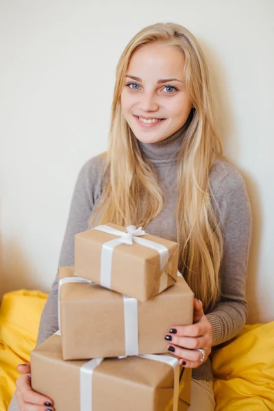 금발 소녀는 벽 근처에 앉아와 그녀의 선물을 열어보고 — 스톡 사진