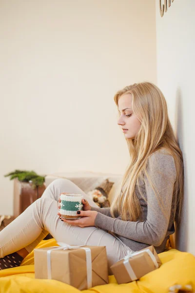Blond meisje drinkig haar koffie, eten cookies en een boek lezen — Stockfoto