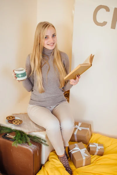 Blonde fille buvant son café, manger des cookies et lire un livre — Photo