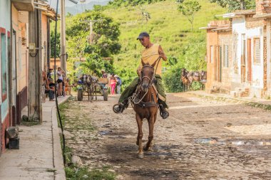 Trinidad, Küba - 15 Temmuz 2018: Atlı bir adam yemyeşil tepeler ve yerel yaşamla çevrili Trinidad Küba 'nın büyüleyici kaldırım taşı sokaklarında geziniyor.