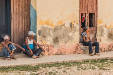 Trinidad, Küba - 15 Temmuz 2018: Dört yaşlı adam Trinidad Küba 'da renkli bir duvar boyunca oturmuş öğleden sonra rahat atmosferinin tadını çıkarıyorlar.