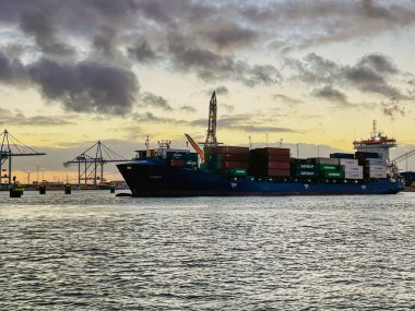 Rotterdam, Hollanda - 22 Kasım 2021: Konteynır gemisi Rotterdam 'a yanaşıyor, otomatik vinçler yoğun limana yük boşaltmaya hazırlanıyor.