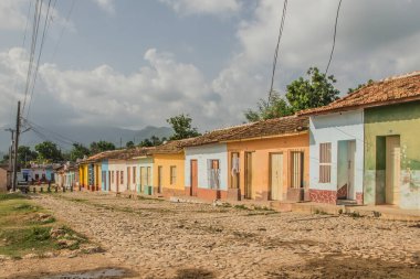 Trinidad, Küba - 15 Temmuz 2018: Canlı pastel evler Trinidad Küba 'daki bu kaldırım taşı caddesinde parçalı bulutlu bir gökyüzünün altında canlı bir atmosfer yaratıyor..