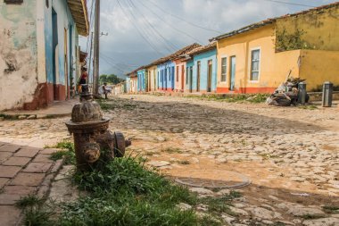 Trinidad, Küba - 15 Temmuz 2018: Trinidad 'daki kaldırım taşı caddeleri Küba kültürünü yansıtan bulutlu bir gökyüzünün altında renkli cepheli evler sergileniyor.