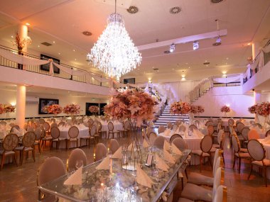 Amsterdam, Hollanda - 23 Mayıs 2025: Bir düğün salonunun içi beyaz masa örtüsü sandalyeleri ve çiçek düzenlemeleri ile süslenmiştir.