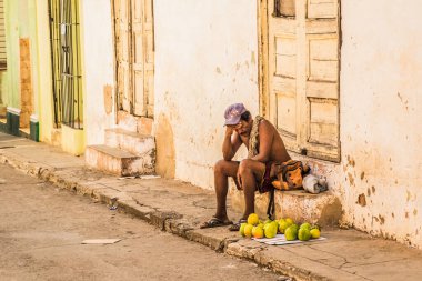 Trinidad, Küba - 15 Temmuz 2018: Trinidad Küba 'da bir adam taze meyvelerle çevrili bir basamakta oturur ve gün içinde dinlenir..