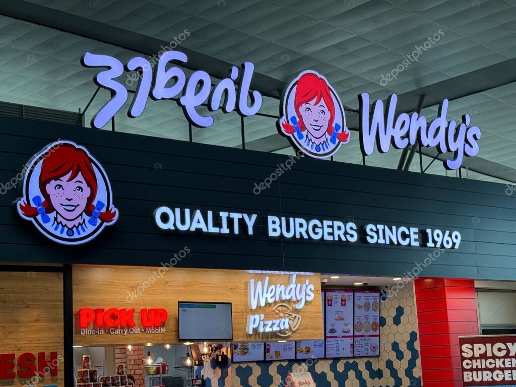 Tbilisi, Georgia - April 28 2025: Brightly lit restaurant sign showcases quality burgers since 1969 in a bustling urban area with varied dining options nearby.