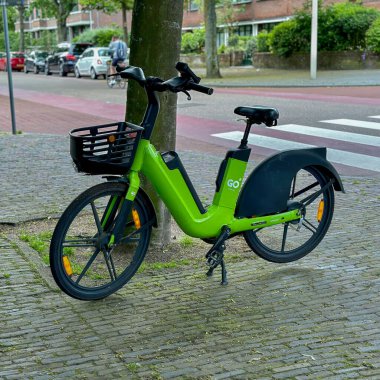 Hollanda, den haag - 23 Mayıs 2024: Elektrikli bisiklet ya da bisiklet paylaşım sistemi adı verilen caddeye park edilmiş bir ağacın yanına git