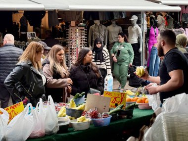 Den Haag, Hollanda - 19 Nisan 2025: İnsanlar Den Haag 'da canlı bir pazara girip taze ürünler keşfediyor ve güneşli bir öğleden sonra sohbet ediyorlar..